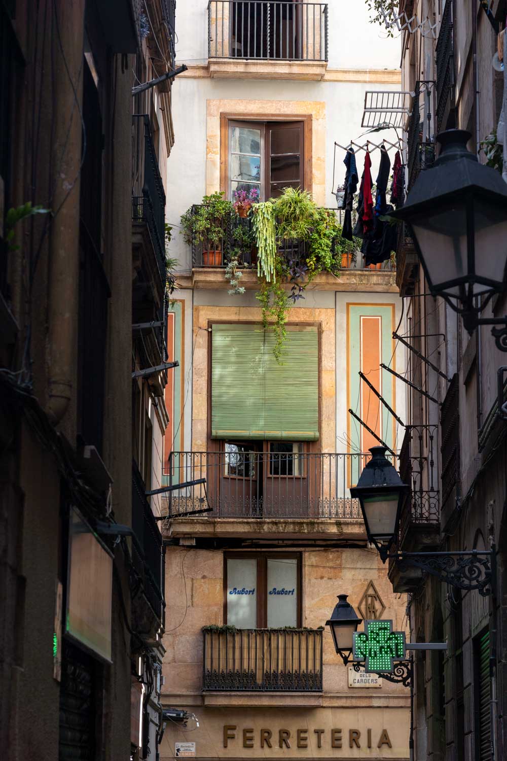 View down narrow Gothic Quarter street, to balconies on building illuminated in sunlight