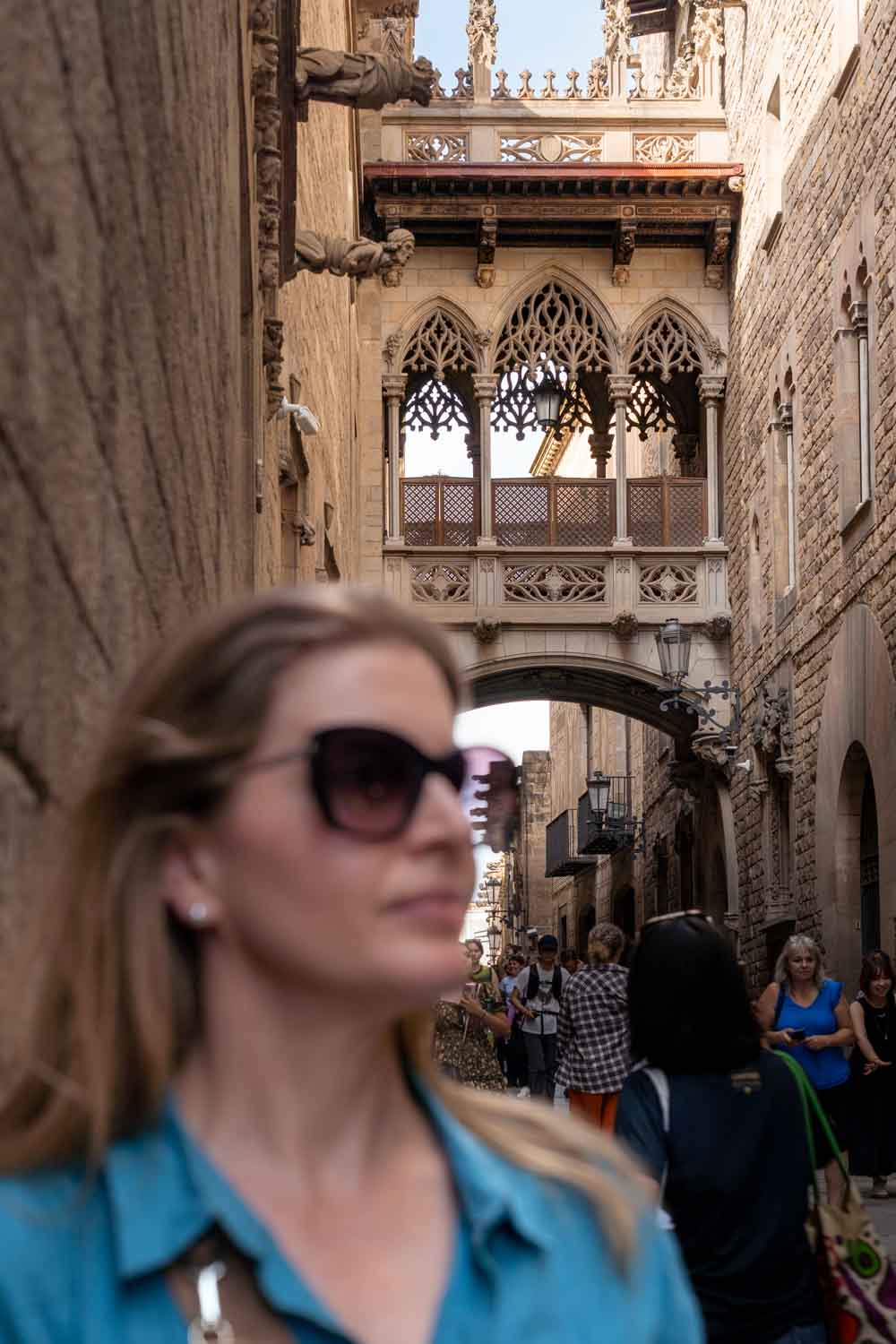 Madam ZoZo standing in Barcelona Gothic Quarter street with Pont Del Bisbe in background