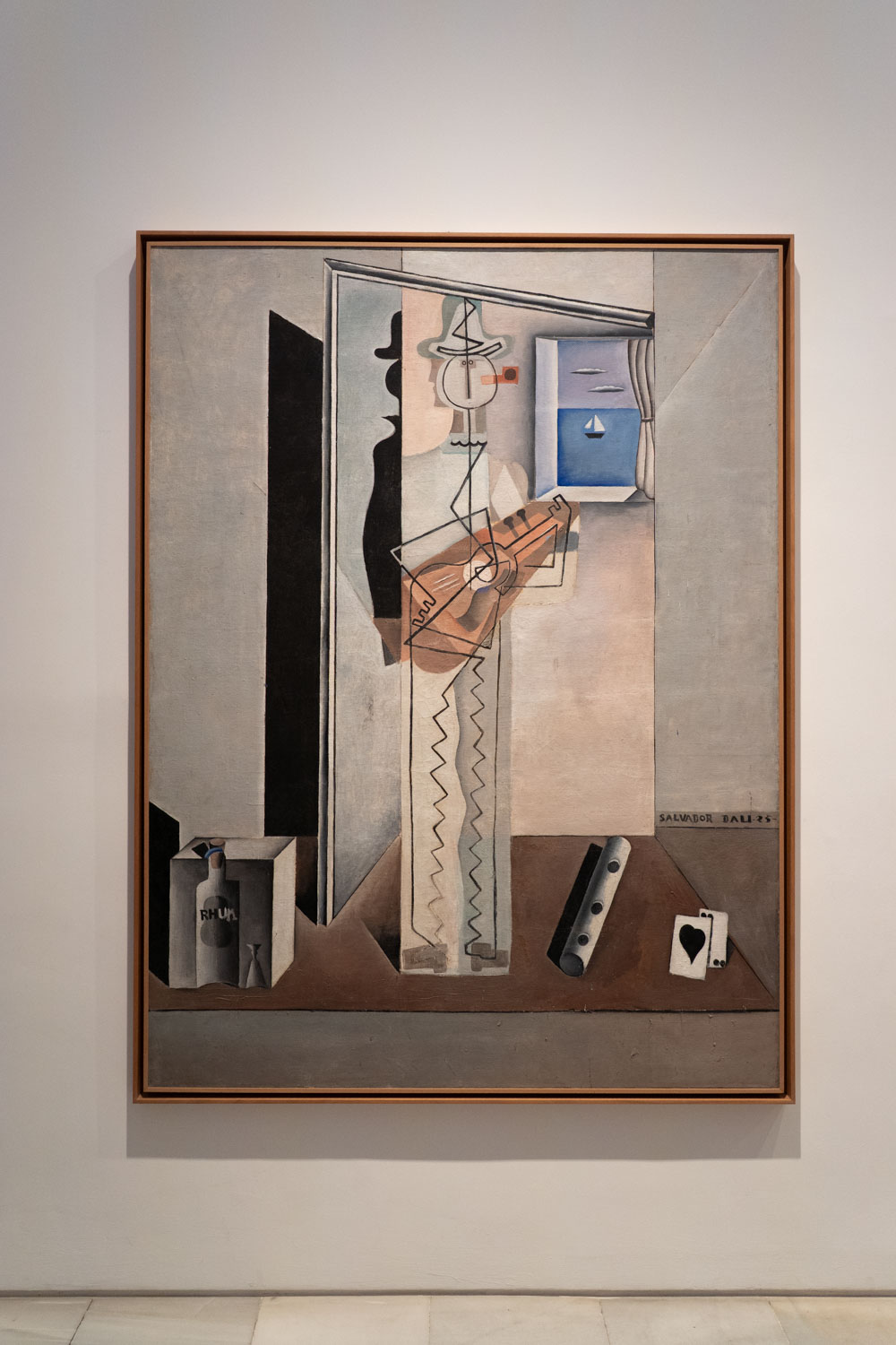 Cubist painting of man playing a guitar by Salvador Dali, hanging on white wall in an art museum