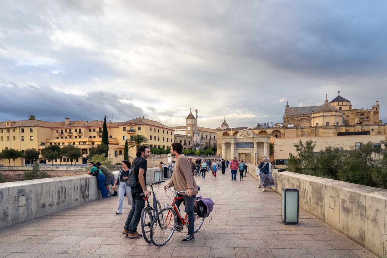 Two local men on bicycles, stop to chat on the Roman Bridge in cordoba