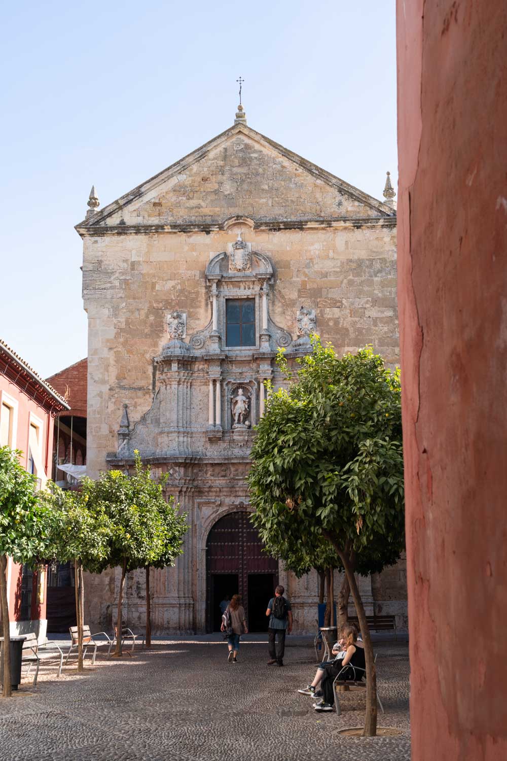 Exterior of historic stone church with foreground of orange trees in patio