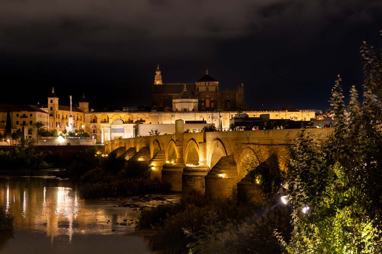 View to Roman Bridge and Historic Centre at night, with stone structures illuminated and reflecting off river water
