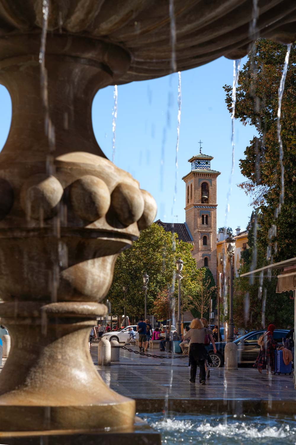Plaza in historic district viewed through water from a fountain, with mountains in distance