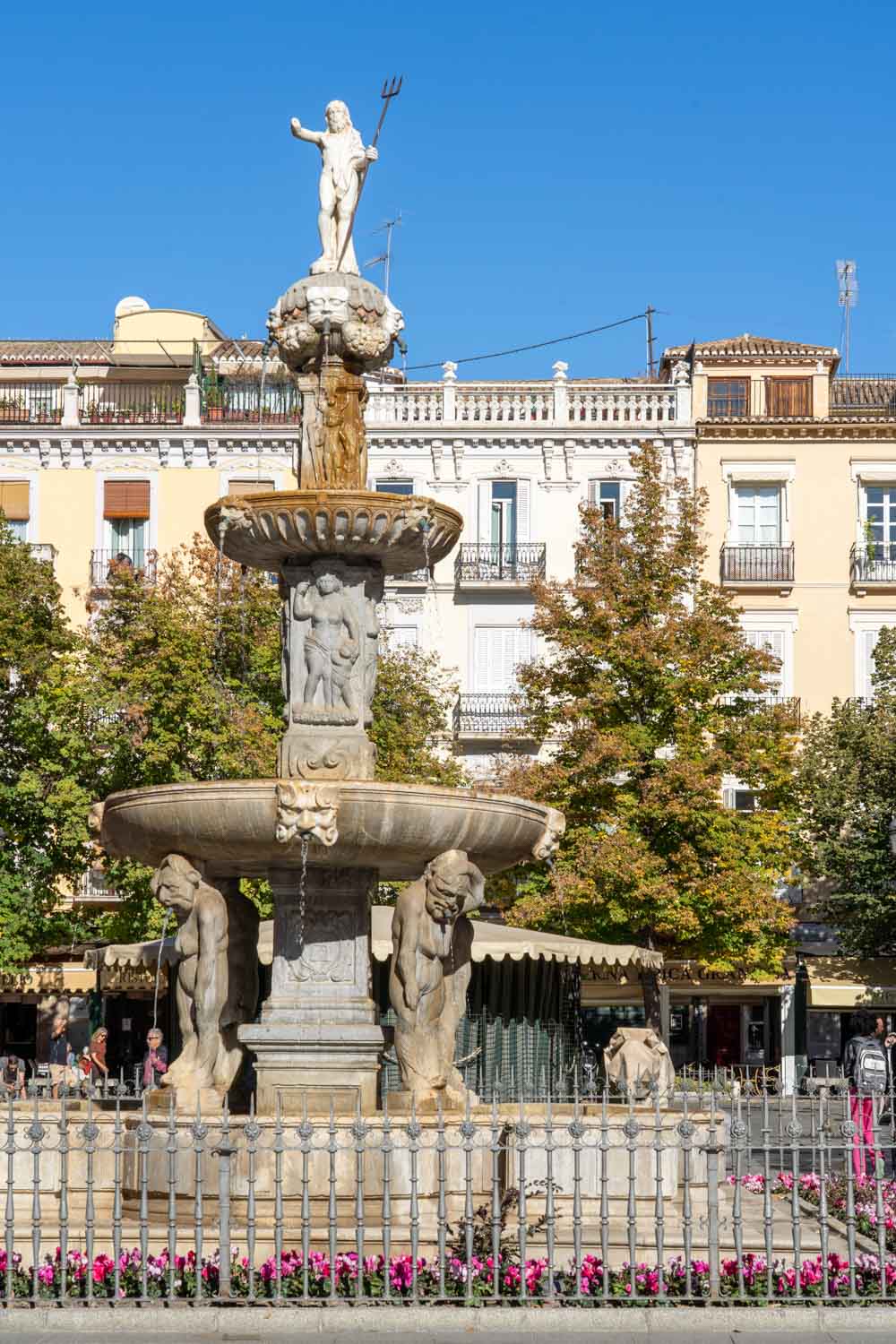 Fountain featuring a sculpture of Neptune, on a sunny day with historic architecture in the background