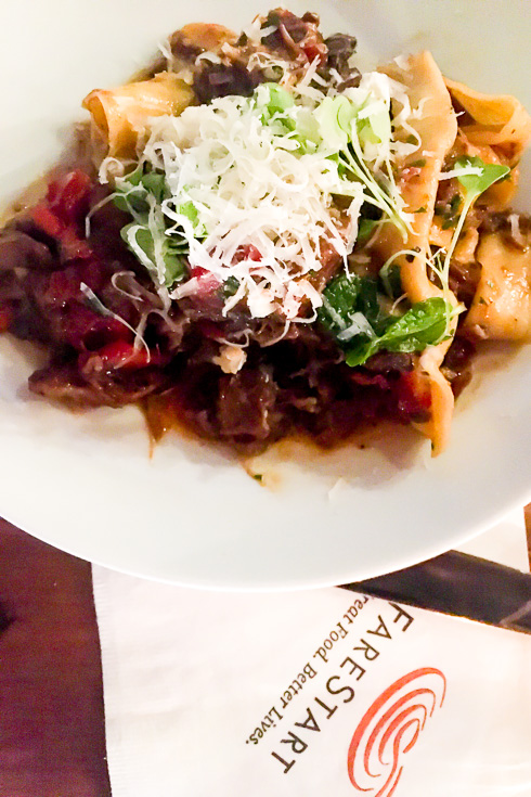 Pasta dish on table with FareStart branded napkin.