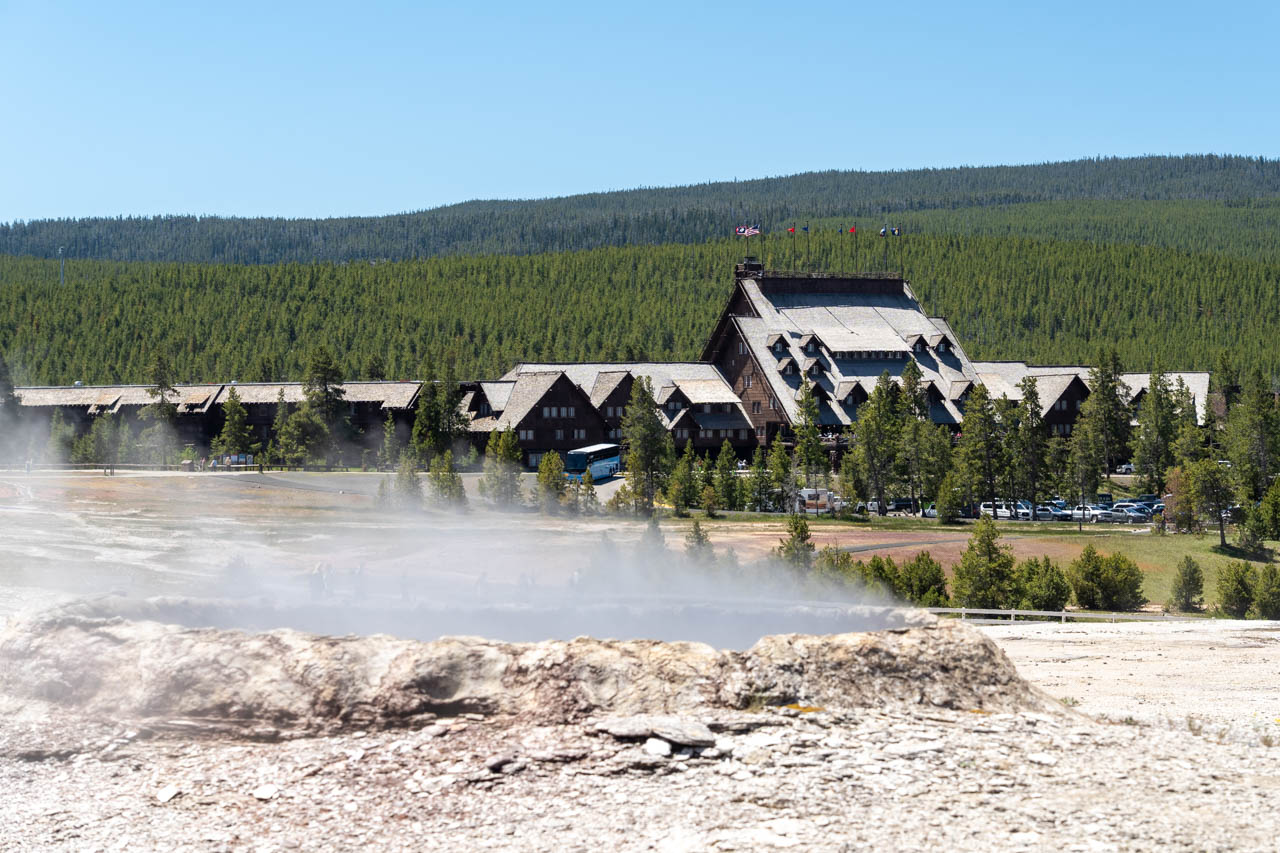 Old Faithful Inn with a steaming geyser in the foreground