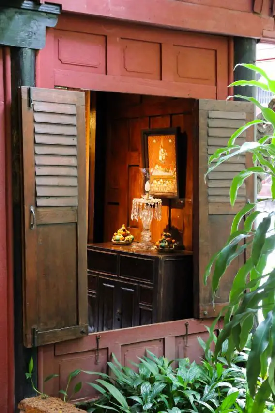 Looking in  window of Jim Thompson House at a crystal lamp and Thai artwork
