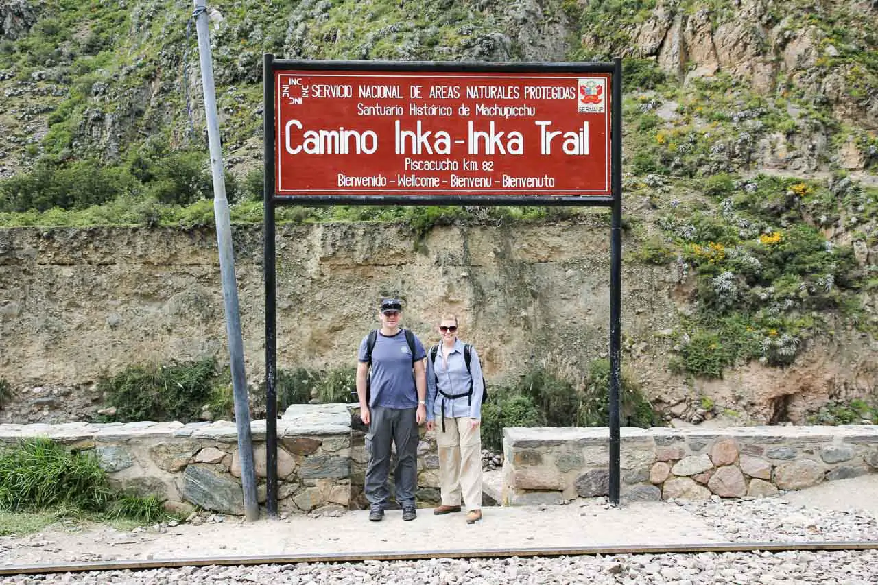 Couple standing under sign reading "Camino Inka - Inka Trail"