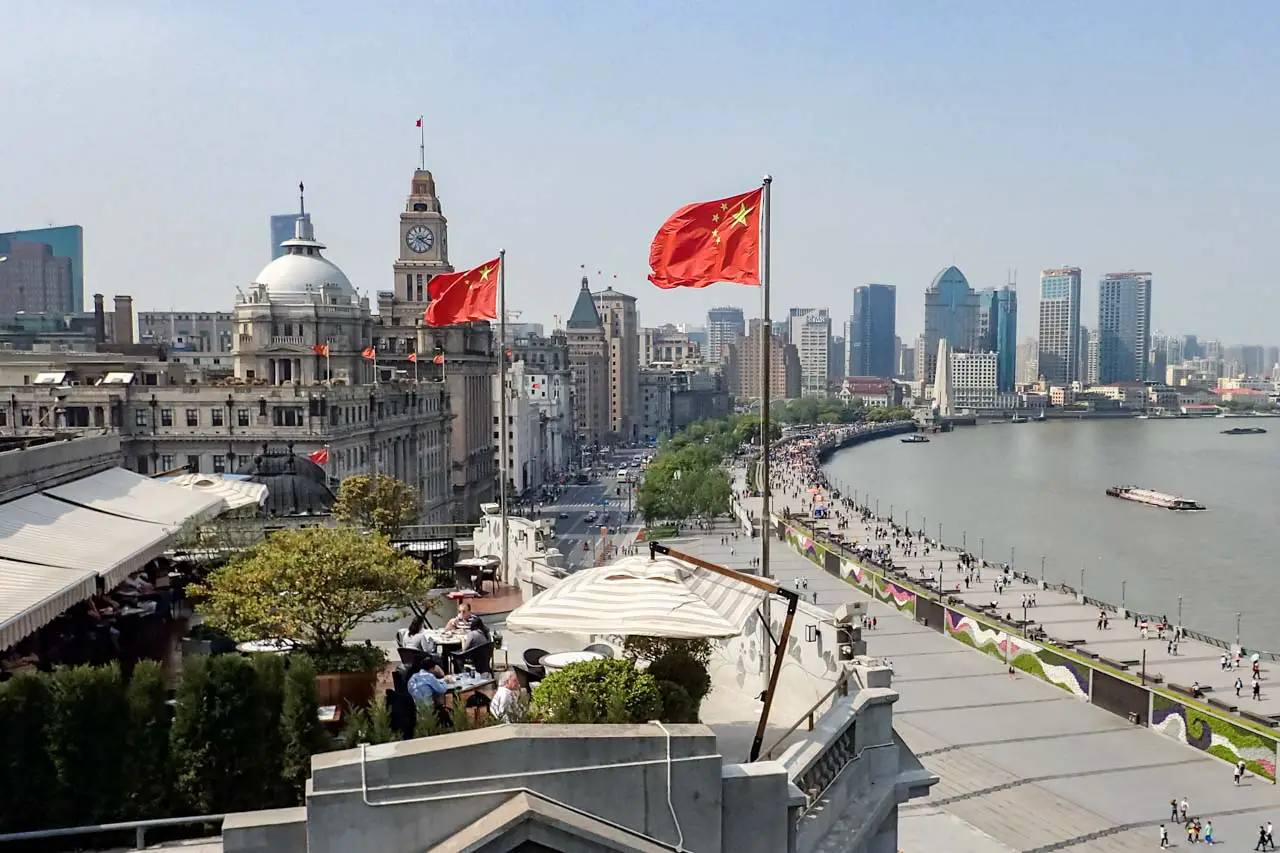 Photo of Chinese flags flying on a rooftop overlooking The Bund and Huangpu River