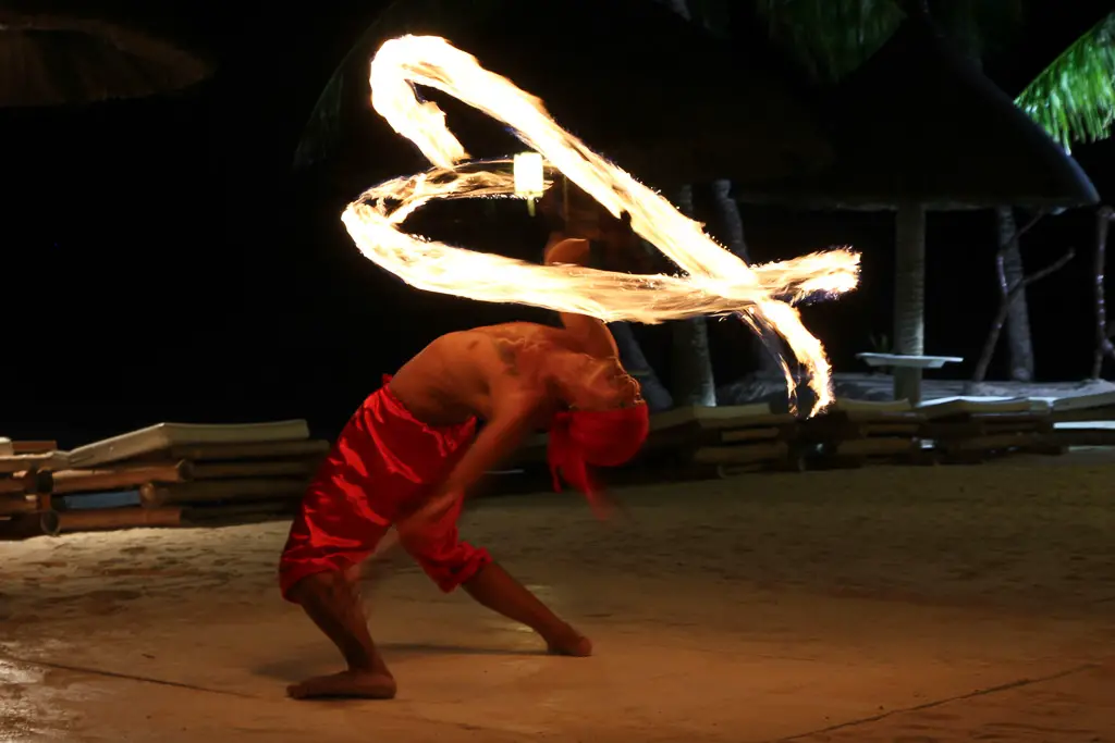 Fire dancer in red performing outside resort on beach