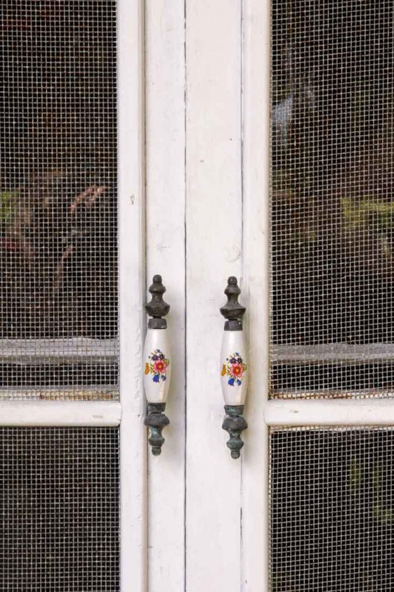Ornate door handles on screen door, decorated with hand-painted flowers