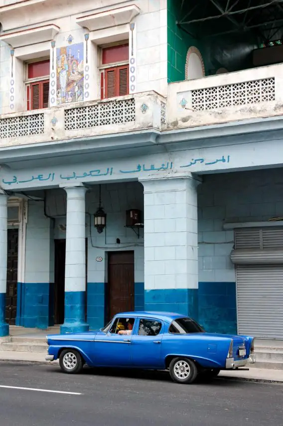Blue classic car parked in front of blue building