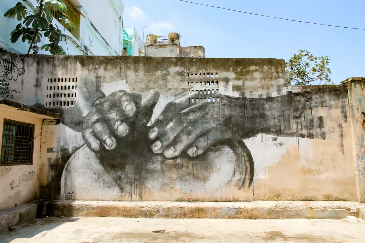 Monochrome painting of hands drumming on a bongo, on a damaged wall