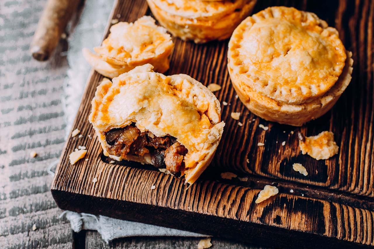 Single serve meat pies on a wooden cutting board