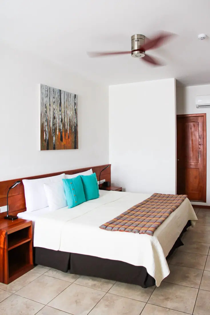 Basic hotel room with queen bed, ceiling fan and air conditioning