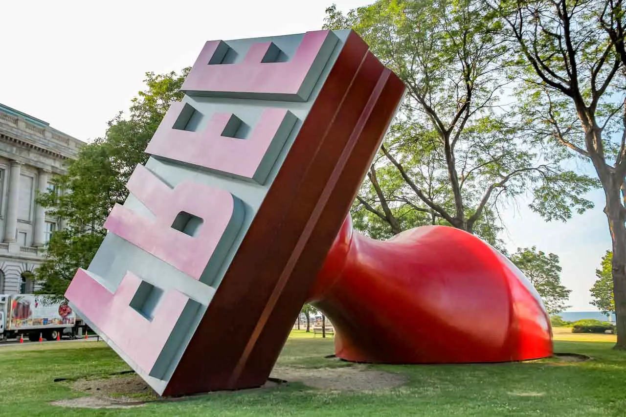 Giant red rubber stamp reading "free" in a park with trees in the background