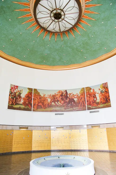 Interior of circular room with green ceiling and large central light embellished like the sun