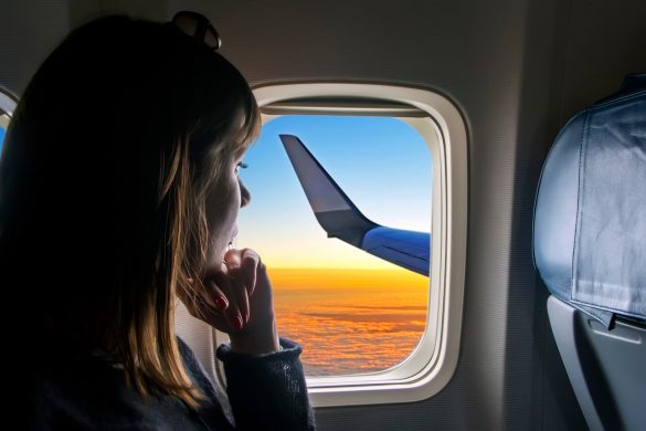Woman looking out plane window at sunset