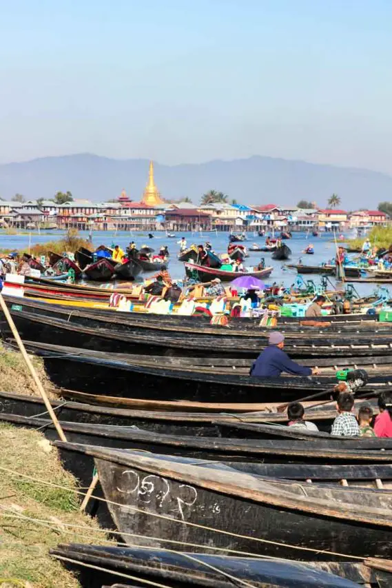 Wooden boats pulled ashore with lake and gold stupa in the background