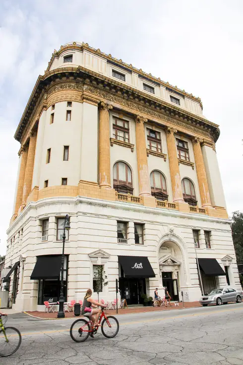 Large, cream, multistory building with curved corners and black awnings on lower floor