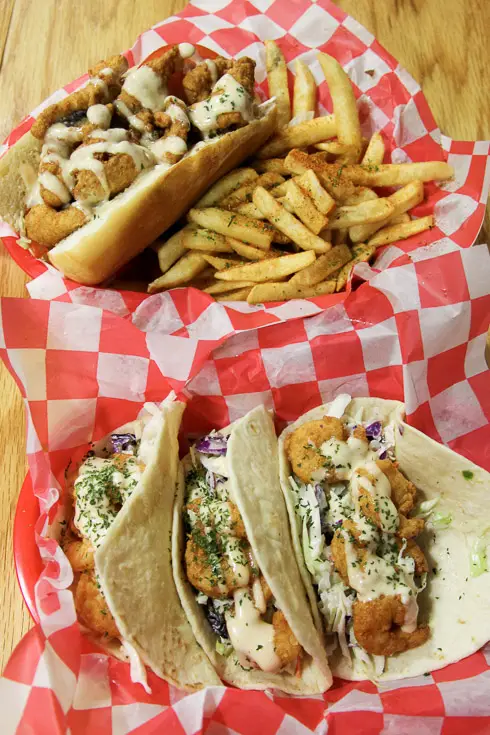 Tacos and po'boy sitting in baskets lined with red and white check paper
