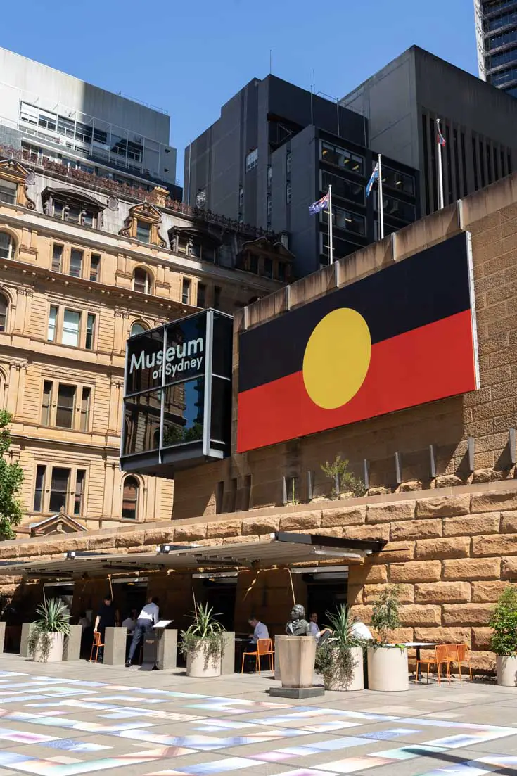 Exterior of the Museum of Sydney with large Aboriginal flag