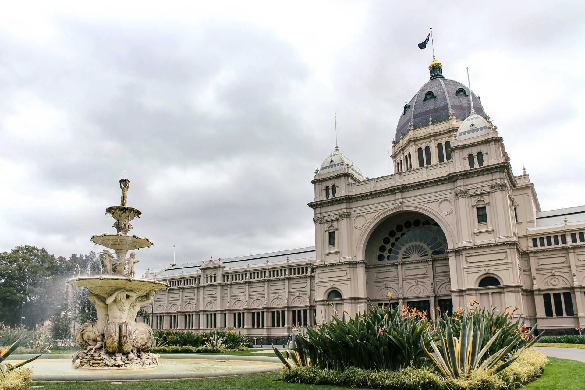 Front facade of historic exhibition building with fountain in foreground