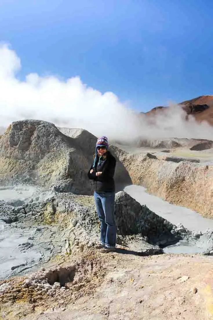 Woman standing among steaming geysers