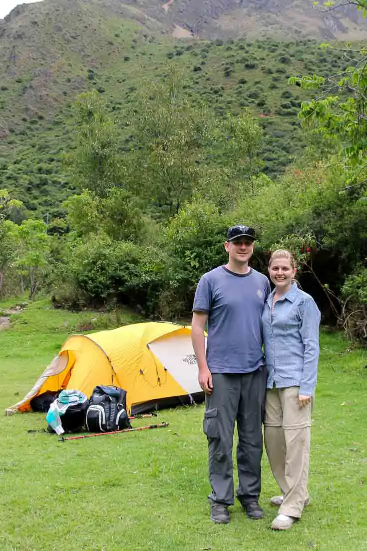Couple standing infront of yellow tent on mountainside
