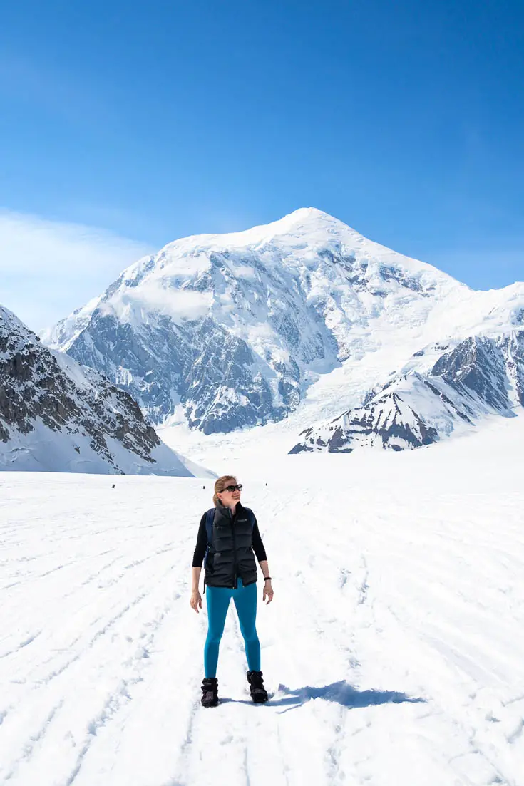 Woman standing on glacier infront of mountain peak
