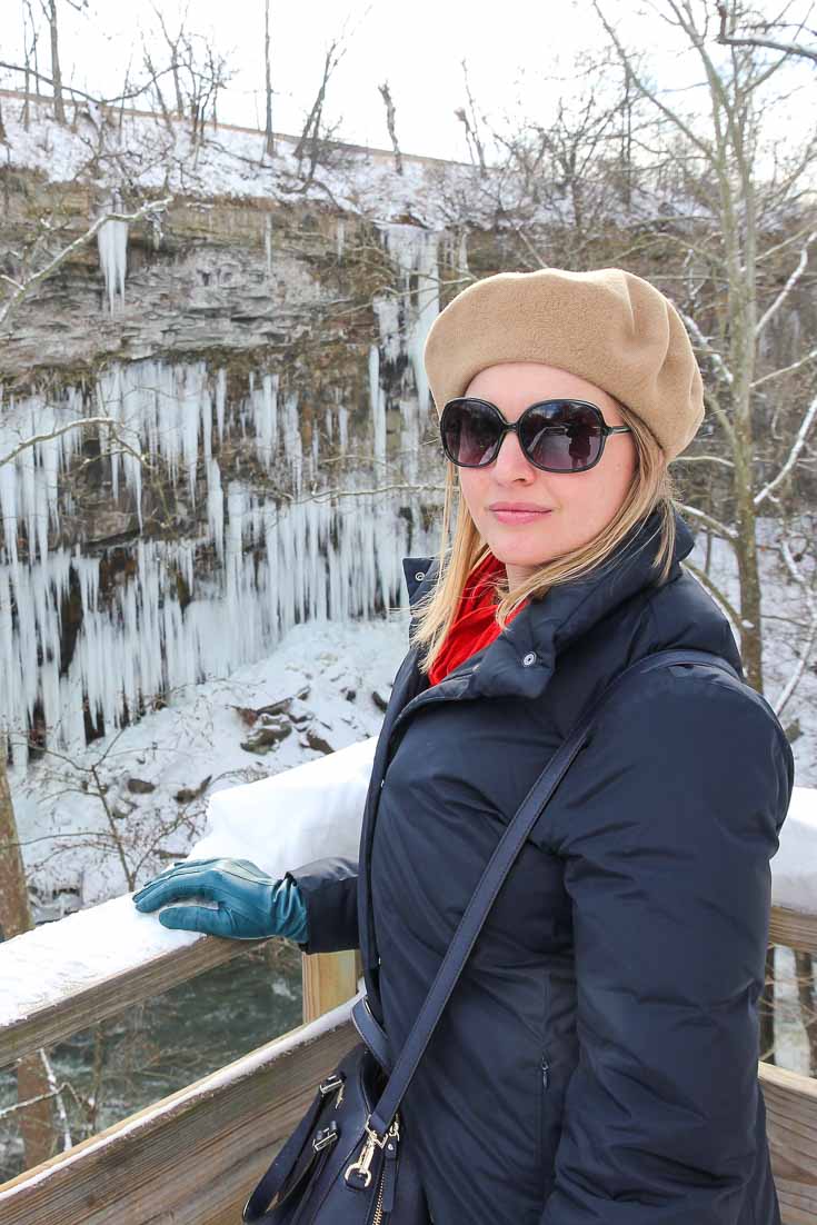 Woman standing on wooden platform overlooking icicles on canyon walls at High Bridge Glens