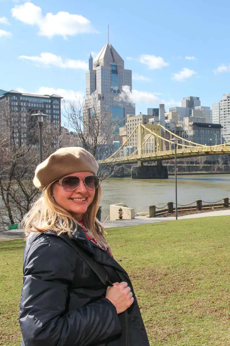 Woman in beret and sunglasses with Pittsburgh skyline in background
