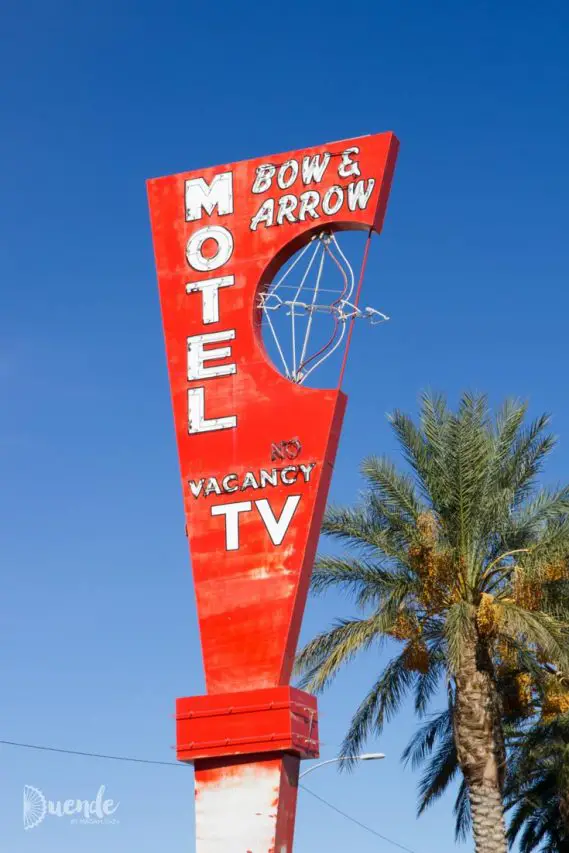 A red and white sign with a neon bow and arrow