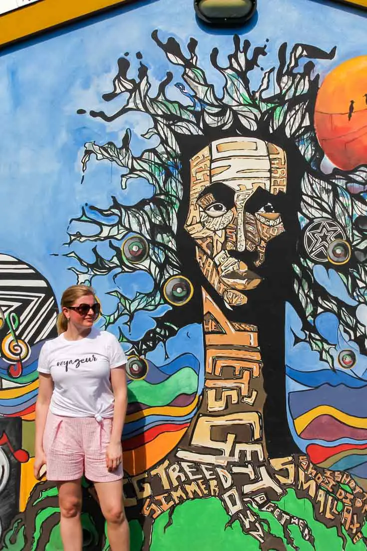 Woman standing beside mural at the Bob Marley Museum, Kingston