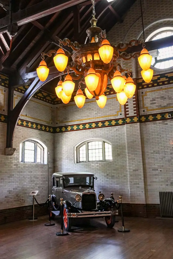 Vintage car inside grand garage with chandelier and tiled walls