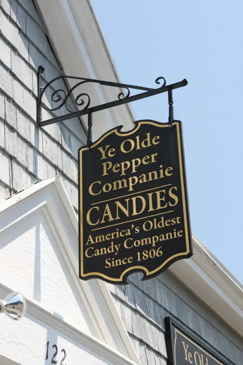 Old fashioned hanging sign outside of shop reading "Ye Olde Pepper Companie Candies - America's Oldest Candy Companie Since 1806