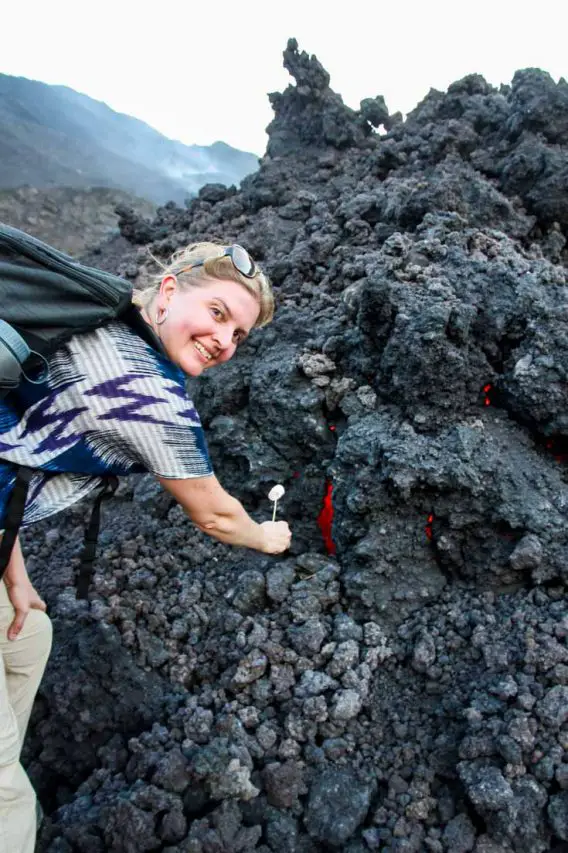 Woman toasting a marshmallow on a lava flow