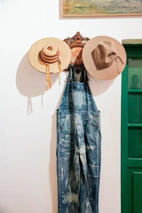 Diego's overalls and hats hanging on a wall