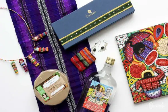 Flat lay of souvenirs from Guatemala including textiles, chocolate, rum, jade and silver earrings, artwork and worry dolls