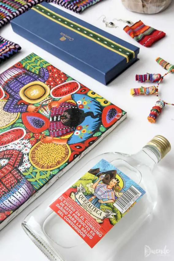 Photo of a bottle of rum, artwork, worry dolls and blue gift box