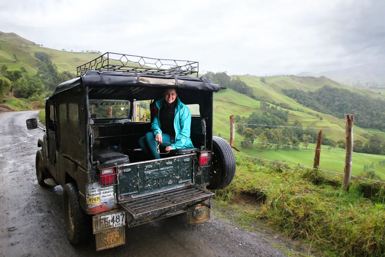 Woman in the back of Jeep on a wet road, in green rural landscape