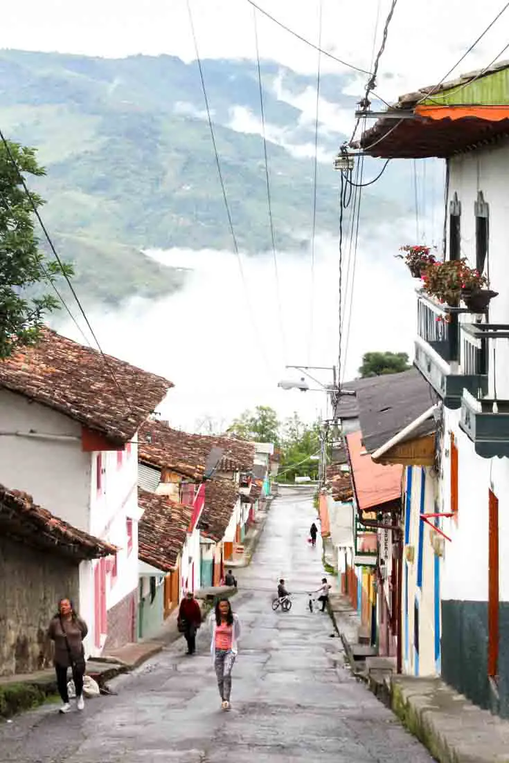 Downward sloping street with clouds and mountains at the end