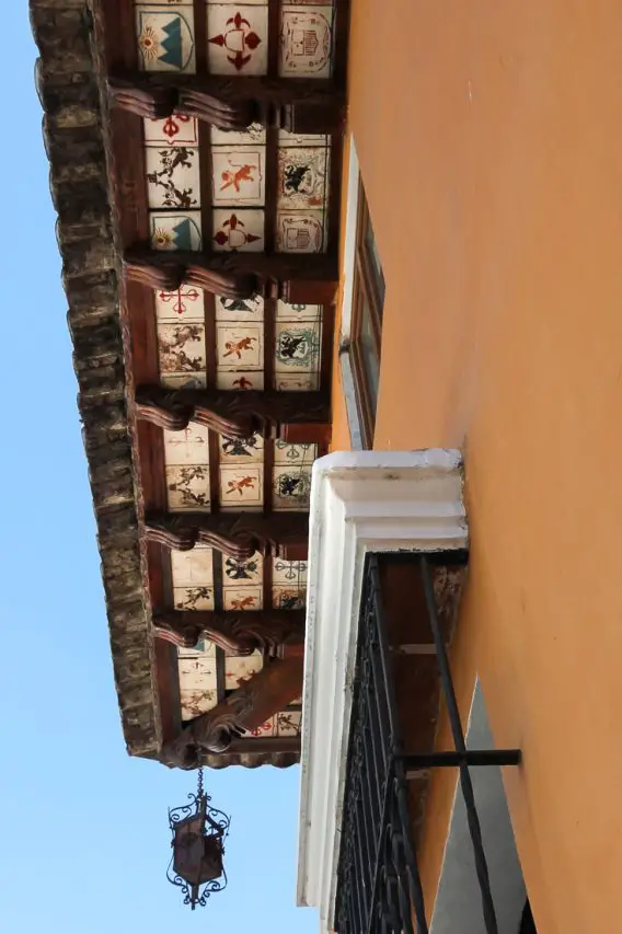 Decorated tiling on underside of building eaves with ornate hanging lantern