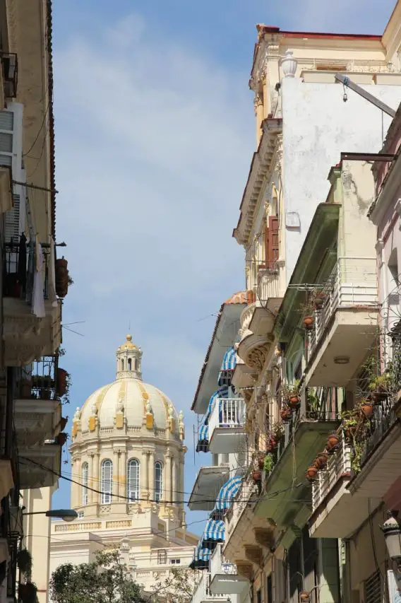 Balconies lining an Old Havana street with cupola of an ornate building in the background