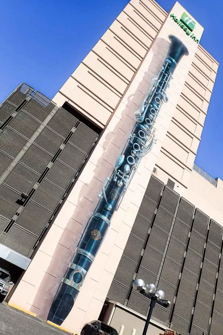 Large scale painting of an upside down clarinet running up the side of multi-story building