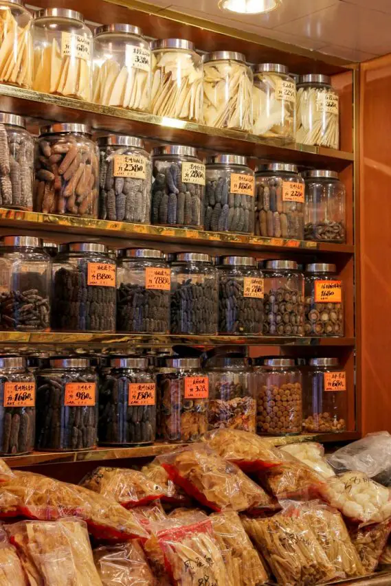 Jars of herbal medicine ingredients on shelves in store