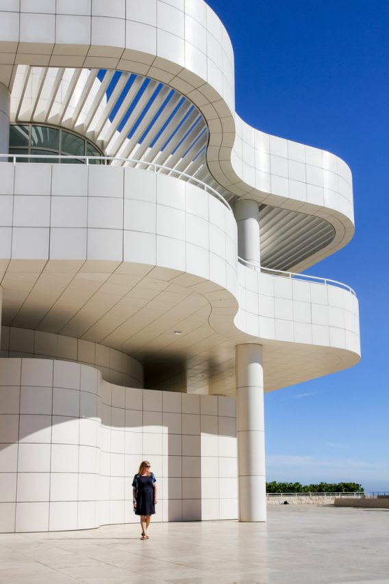Corner of curved white contemporary building with woman standing below