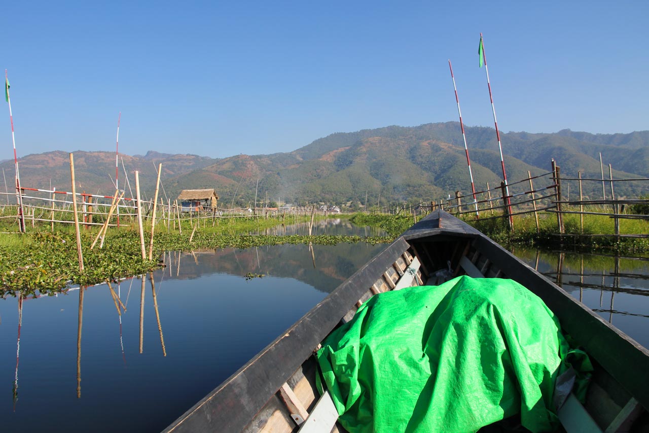 Hydroponic crops and bow of boat in foreground, mountains in background
