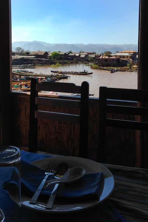 Photo with table set for lunch in foreground, with open window looking onto a lake and mountains behind