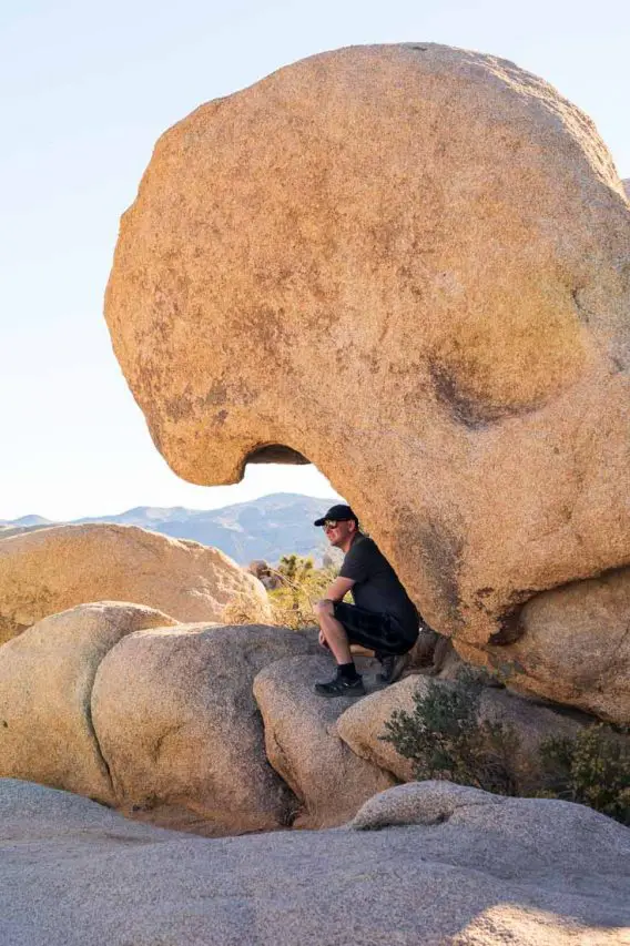 Man sitting under rock that looks like crashing wave